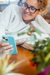 Mature woman using her smartphone at home in various situations. From socializing and working to...