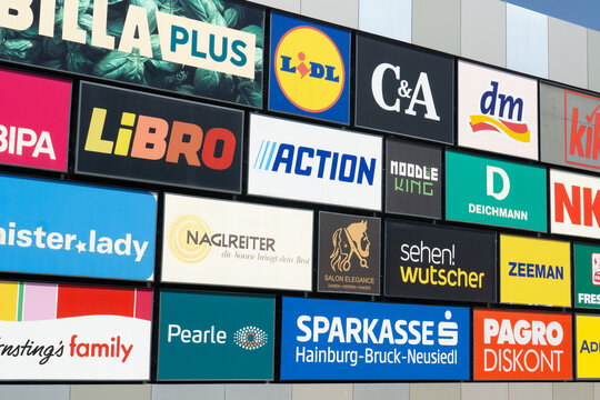 Austria, Hainburg an der donau, Europe - July 05, 2025: Photo of various retail and service brand signs mounted on a commercial building facade in Europe, showcasing recognizable store logos.