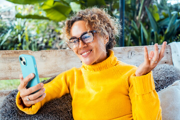 Curly-haired woman in her 40s using smartphone outdoors. Modern lifestyle with technology,...