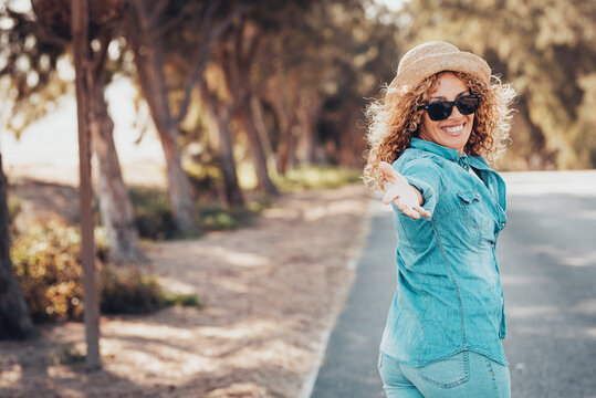 Portrait of wonderful white female model with curly blonde hair expressing energy on a good day in Europe. Beautiful curly woman smiling and walking with trees behind her. - Powered by Adobe