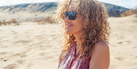 Portraits of a joyful curly-haired woman with sunglasses enjoying a summer day at the beach. Happy...
