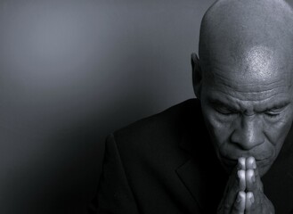 man praying to god with hands together Caribbean man praying with black background with people stock photo stock image