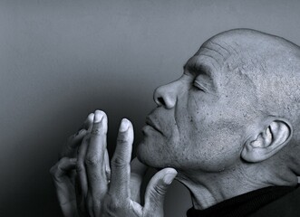 man praying to god with hands together Caribbean man praying with black background with people stock photo stock image