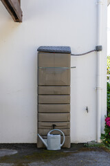 Un réservoir d’eau de pluie installé contre un mur extérieur.