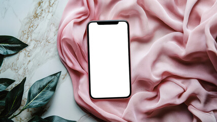 A cell phone with a white screen lies on a flowing pink cloth lying on a marble table next to a green plant. Phone mockup, top view. Demonstration of the phone screen for advertising a women's store