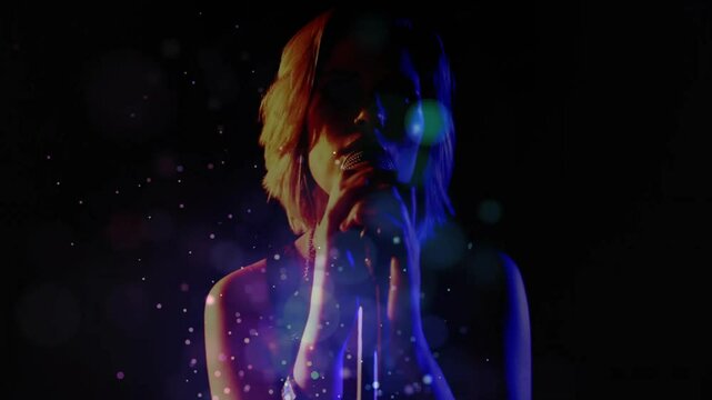Teenage singer bringing hands to microphone, starting song amid colored lights, particle effects