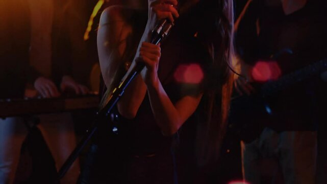 Camera pulling back revealing singer gripping vintage mic singing for music performance with bokeh
