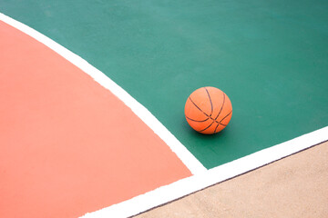 Basketball on colorful green and orange with white outline of outdoor basketball court