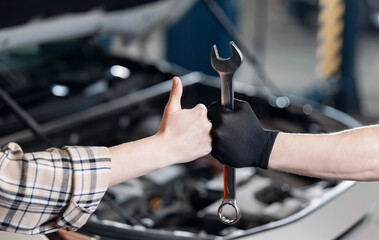 auto mechanic hold wrench and woman thumb up hand in car repair garage service