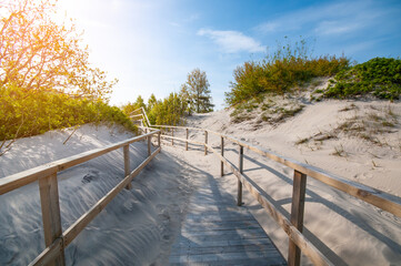 Wooden stair at dunes leading  to the sand beach