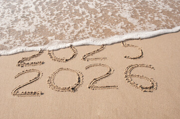 Inscription 2025 and 2026 numbers written on sand.  New Year 2025 replace 2026. Concept on the sea beach
