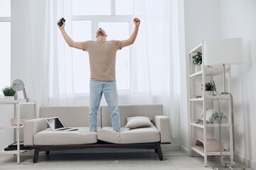 Fototapeta premium Energized man celebrating a digital detox at home, amid a blend of work and relaxation, embracing authentic imperfection and mental well-being.