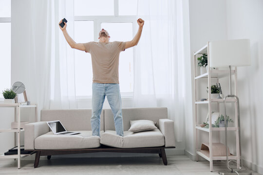 Energized man celebrating a digital detox at home, amid a blend of work and relaxation, embracing authentic imperfection and mental well-being.