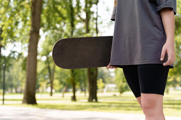 Anonymized view of a skateboarder with their gear in a serene park backdrop, offering a clean,...