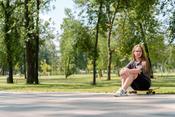 Portrait of a carefree teenage girl dressed in casual summer attire as she casually sits atop a...
