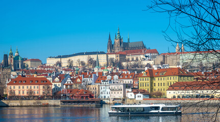 Prague, Czech Republic. Modern electric Boat tour vessel navigating the Vltava River, with historic riverfront buildings