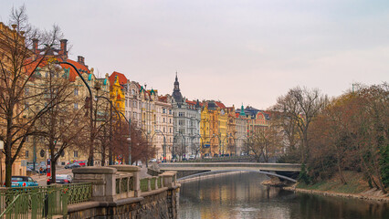 Prague, Czech Republic. Colorful historic buildings lining a tranquil Prague canal, with a modern...