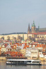 Prague, Czech Republic. Modern electric Boat tour vessel navigating the Vltava River, with historic riverfront buildings