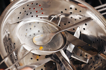 Metal kitchen utensils close-up. Colander, strainer and cutlery in stainless steel. Used dirty...