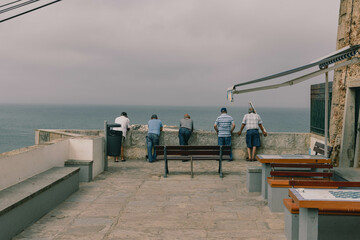 Five old men standing and watching the ocean together -  view from behind
