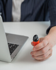 Faceless businesswoman smokes disposable vape and works on laptop. 