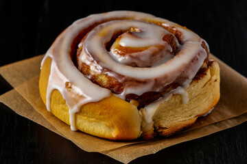 Delicious cinnamon roll with sweet icing on brown paper perfect for breakfast or dessert treat food photo