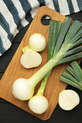 Green onion on cutting board on black wooden background. Vertical photo