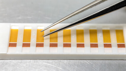 Nitrite test strips with chemical reactive pads and metal tweezers used for detecting nicotine contamination liquids with precise color change