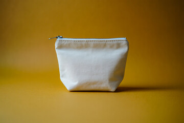 Beige canvas zipper pouch small makeup bag cosmetic bag travel pouch on yellow background studio shot