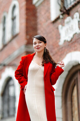Elegant businesswoman wearing red jacket standing at a low wall