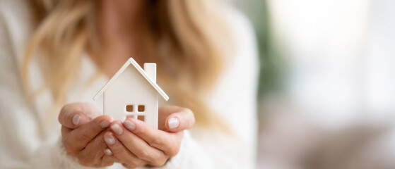Woman showcases house model to illustrate real estate and architectural concepts in a softly lit environment. concept of a real estate agent, loan for buying a house, housing