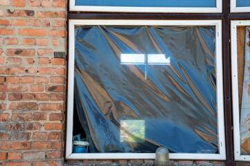 Black plastic covers a window, hinting at ongoing renovations in an urban environment, while light...