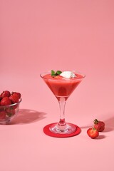 Non-alcoholic strawberry cocktail with ice cream scoop in triangle martini glasses on plain pink background. Valentine's day concept.