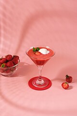 Non-alcoholic strawberry cocktail with ice cream scoop in triangle martini glasses on plain pink background. Valentine's day concept.