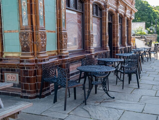The exterior of an old and traditional public house with tables and chairs outside