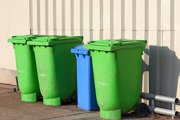 Green and blue rubbish bins stand by the wall