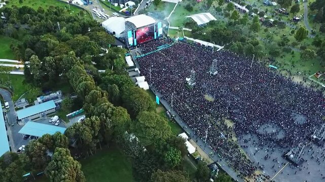 Toma a&eacute;rea de concierto de Rock al Parque en Bogot&aacute; Colombia, en el parque Simon Bolivar, donde se ven personas bailando y pogueando en c&iacute;rculos mientras la tarima enciende y apaga luces del show.