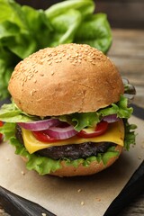 Delicious hamburger with patty and cheese on table, closeup