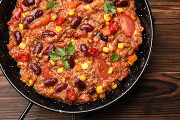 Tasty chili con carne in baking dish on wooden table, top view