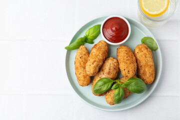 Tasty fried croquettes, basil and sauce served on white tiled table, top view. Space for text