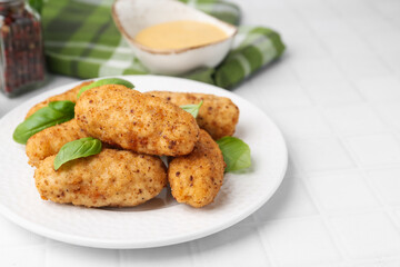 Tasty fried croquettes, basil and sauce on white tiled table, closeup. Space for text
