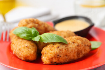 Tasty fried croquettes, basil and sauce on table, closeup