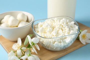 Fresh dairy products and jasmine flowers on light blue background, closeup