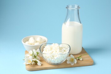 Fresh dairy products and jasmine flowers on light blue background