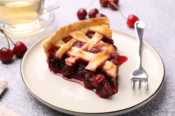 Piece of tasty cherry pie, berries and fork on grey textured table, closeup