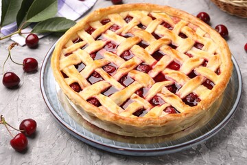 Tasty cherry pie and berries on grey textured table, closeup