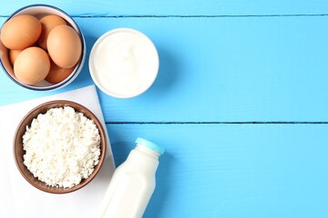 Fototapeta premium Different dairy products and eggs on light blue wooden table, flat lay. Space for text