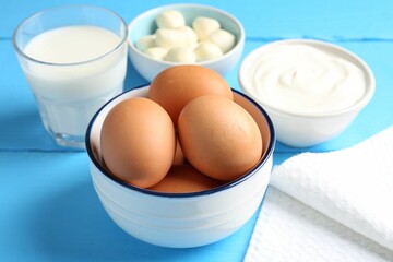 Different dairy products and eggs on light blue wooden table, closeup