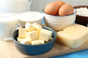 Different dairy products and eggs on light blue table, closeup