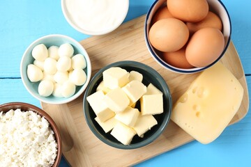 Different dairy products and eggs on light blue wooden table, flat lay